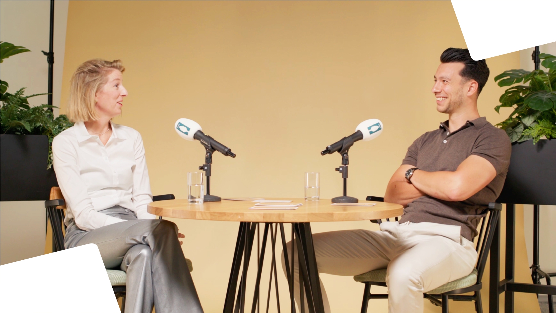Two people recording a podcast: a woman and a man engaged in a lively conversation, seated at a table with microphones.