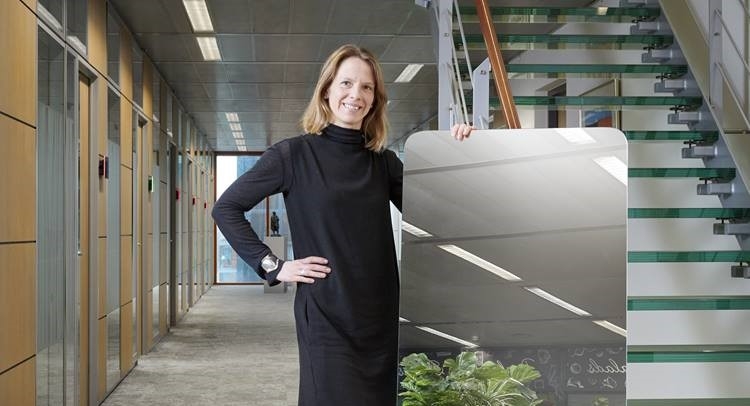 Photo of a woman holding up the Van Lanschot Kempen mirror near the staircase on the 7th floor in the Amsterdam office