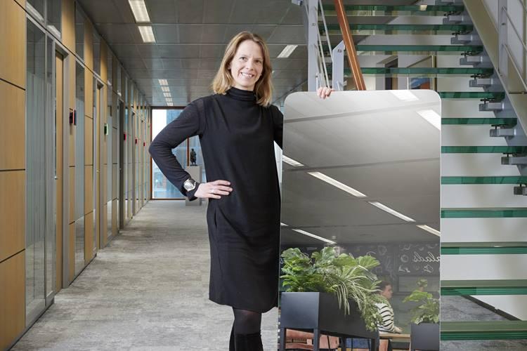 Photo of a woman holding up the Van Lanschot Kempen mirror near the staircase on the 7th floor in the Amsterdam office