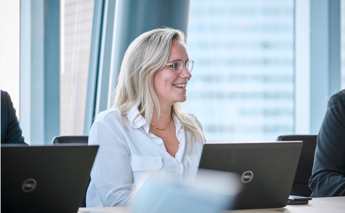 Blond woman smiling in a professional setting, exuding confidence and approachability.