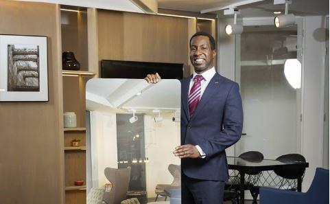 Photo of a man with a wide smile holding up the Van Lanschot Kempen mirror in an office