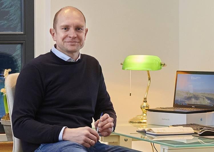Photo of Dirk Saltzherr smiling and sitting down 