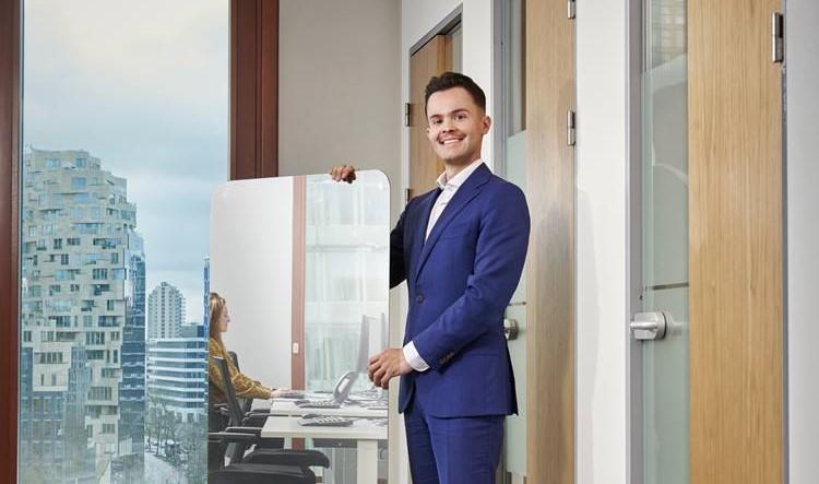 Photo of a smiling man in a blue suit holding up the Van Lanschot Kempen mirror