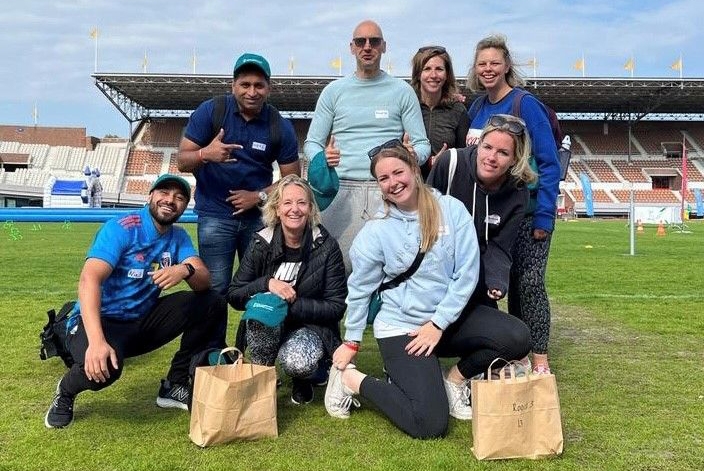 Van Lanschot Kempen volunteers sitting on the grass at the Amsterdam Olympic Stadium